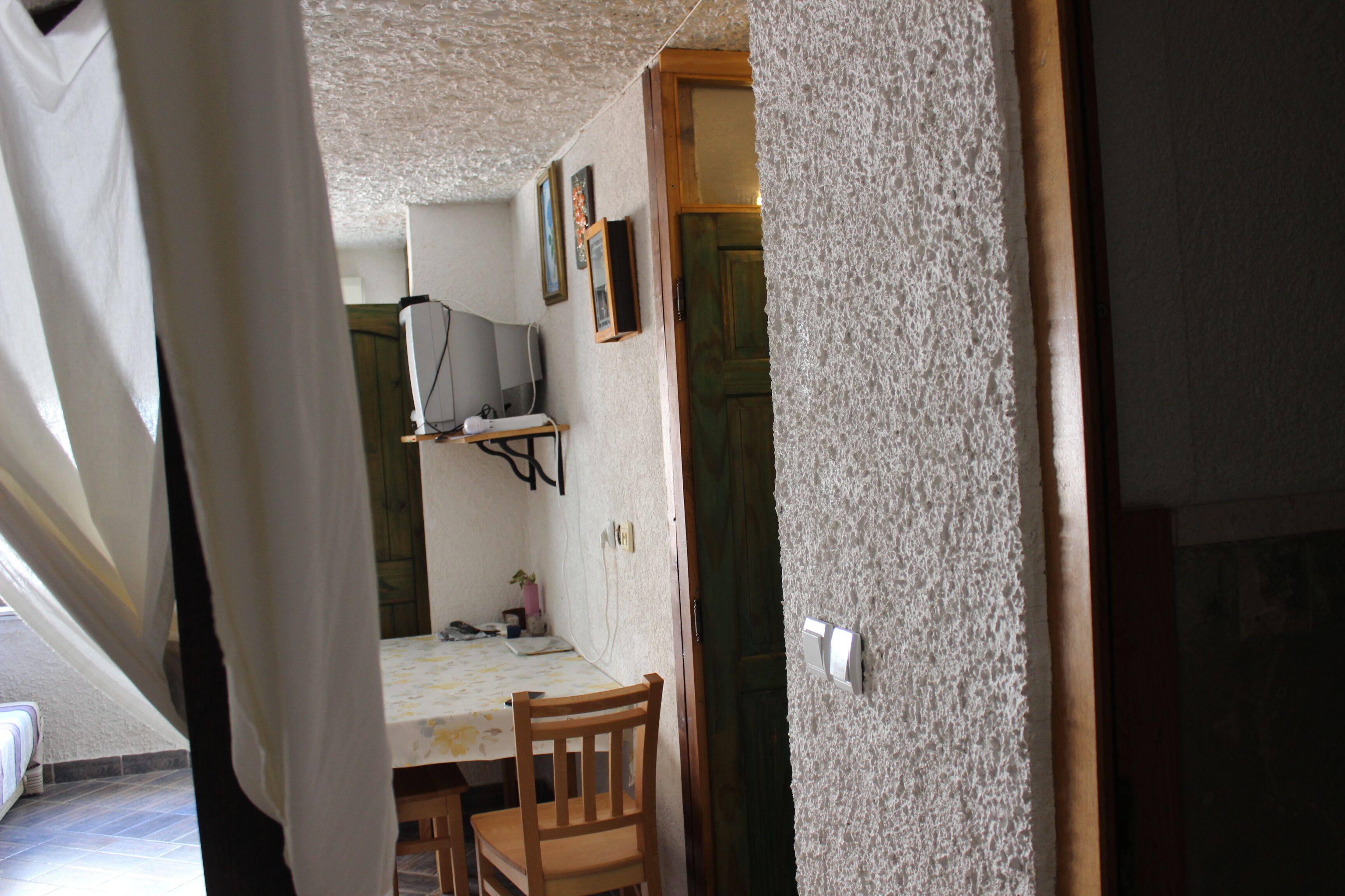 Una habitación con una mesa de comedor, sillas, televisor y una puerta.