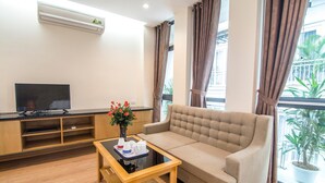 Un salon moderne avec un canapé, une table basse, un téléviseur à écran plat et une plante en pot.