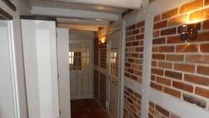 Ein Flur mit Backsteinwand, einer weißen Tür und einer Wandleuchte.