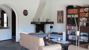 Una sala de estar con chimenea, un sofá, una estantería y una mesa de centro.