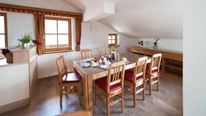 Comedor con mesa de madera dispuesta para cuatro personas, rodeado de sillas con cojines rojos.