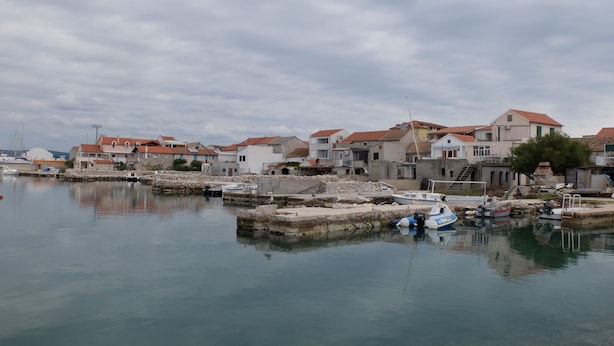 A coastal village with stone buildings, a calm harbor, and boats docked. - Fischer Fritz, bed & bike (Betina;Murter)