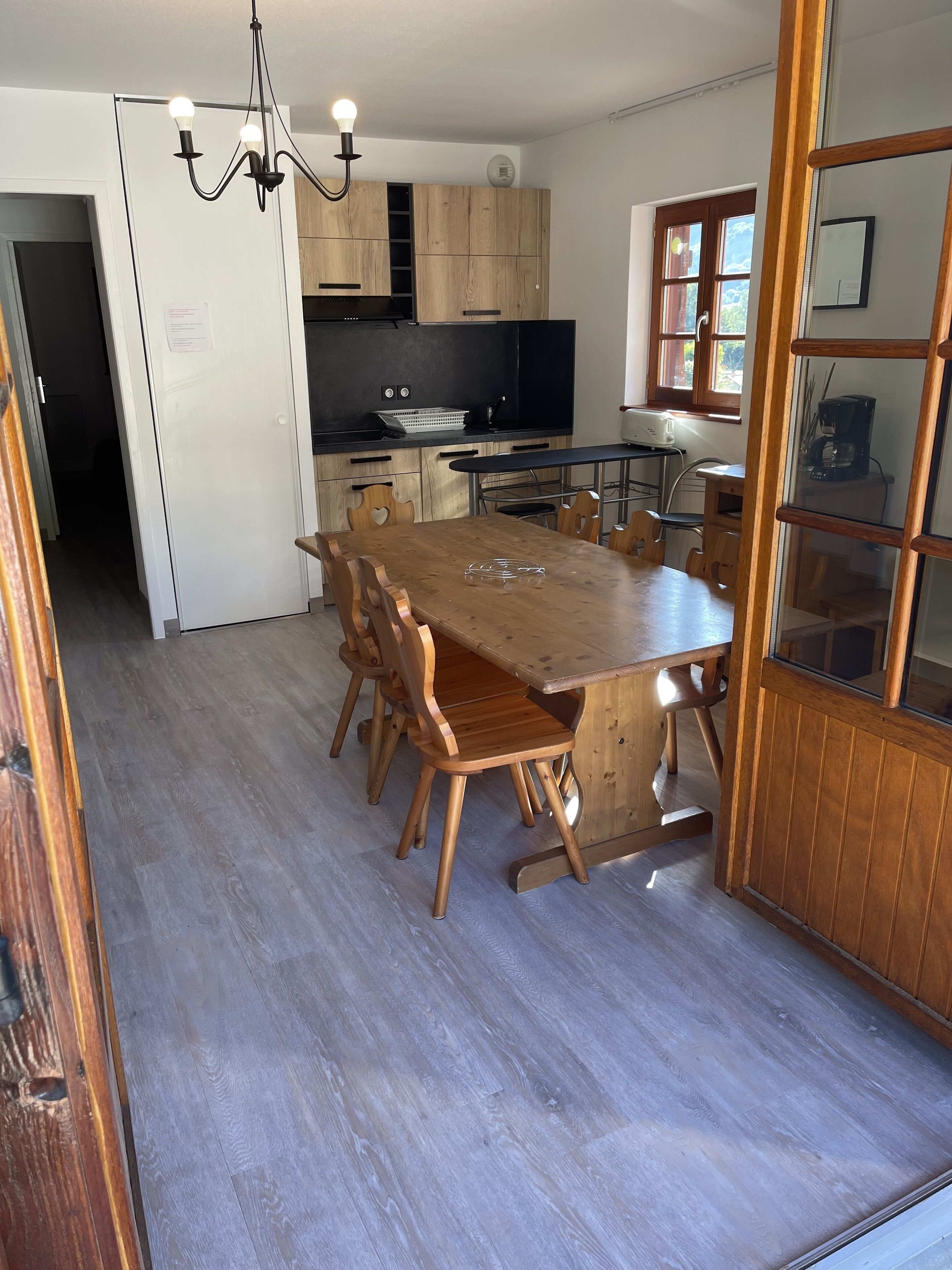 Una cocina moderna con armarios de madera, una mesa de comedor grande y una araña.