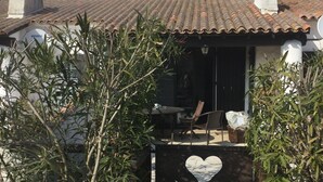 Una casa con tetto a tegole, parabola e un'apertura a forma di cuore nel cancello.