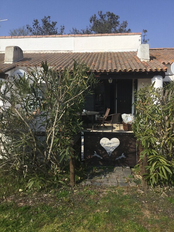Una casa con tejado de baldosas, antena parabólica y un recorte en forma de corazón en el portón.