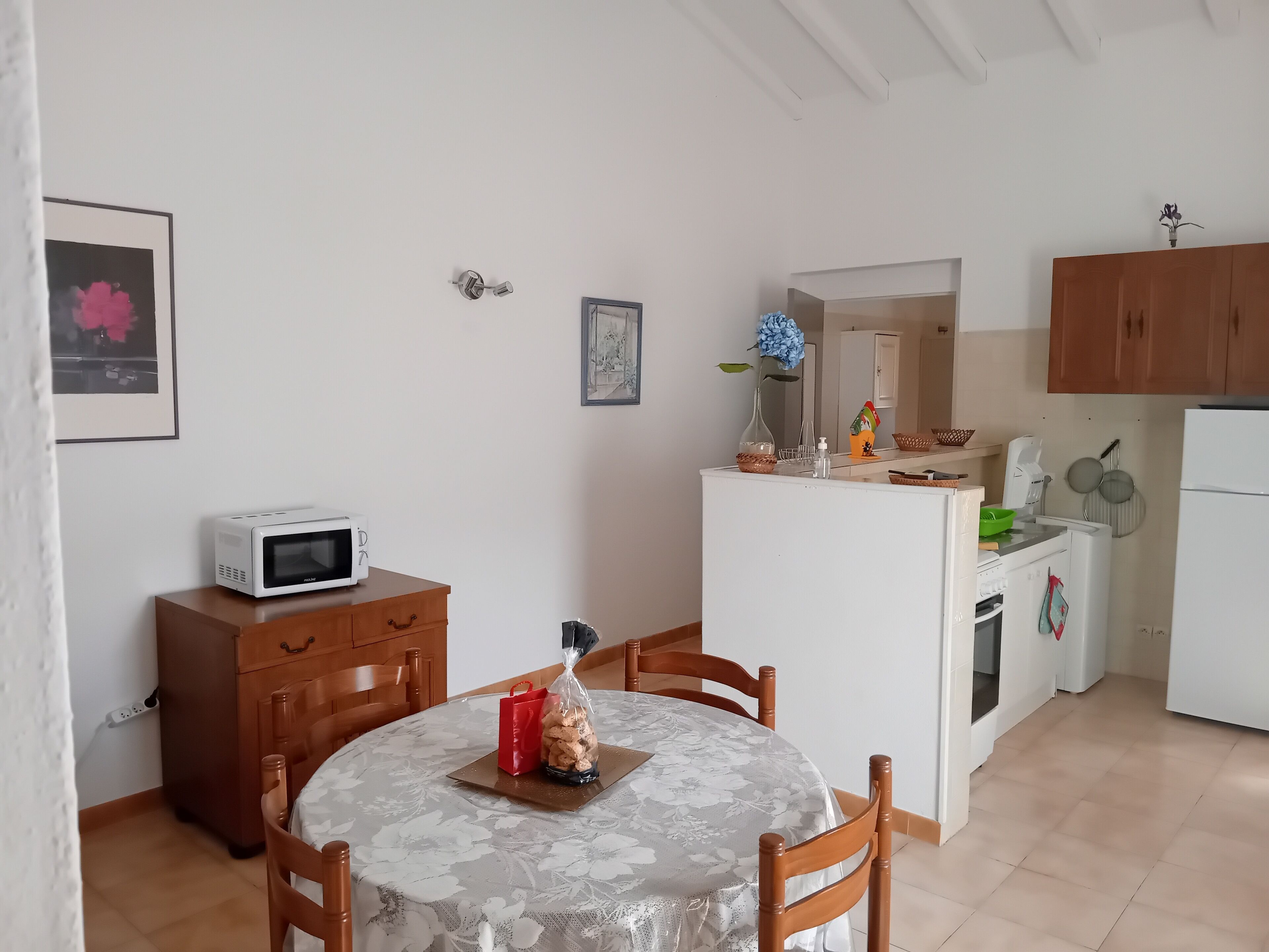 A compact kitchen with a dining area, featuring a microwave, wooden cabinets, and a table with chairs.