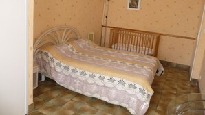 A bedroom with a bed, a crib, a nightstand, and a wall-mounted lamp.