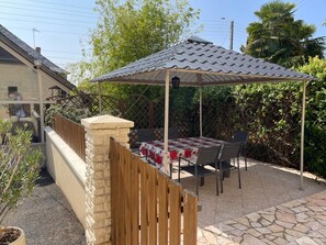 A patio with a table and chairs, a covered area, and a stone pathway.