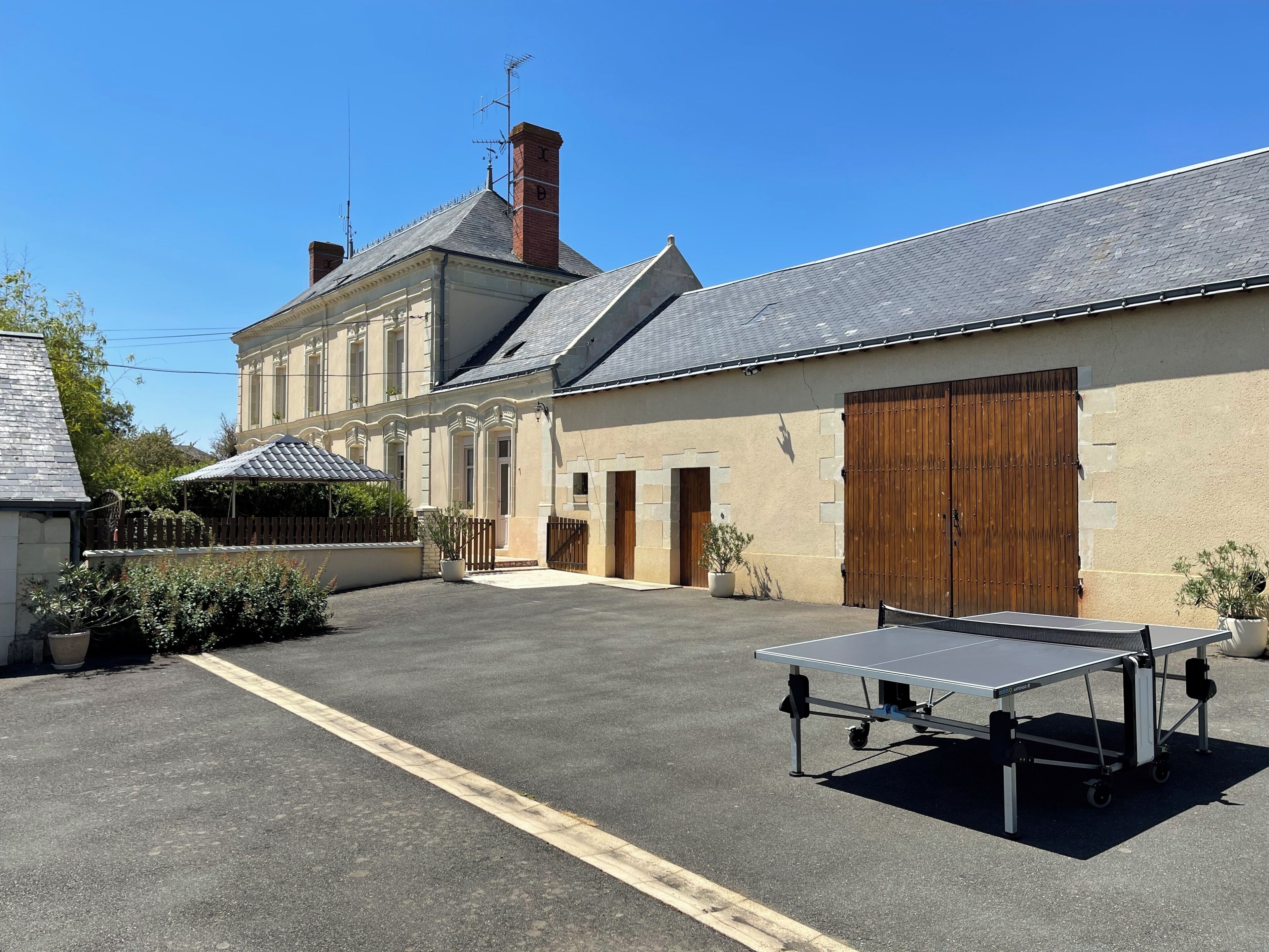Un bâtiment doté d’un grand portail de garage, d’une table de ping-pong et d’un jardin clos.
