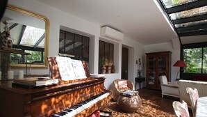 A spacious living room with a grand piano, comfortable seating, and large windows allowing natural light. - Large house with plenty of charm (Aureilhan)