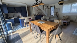 Een kleine leefruimte met een eethoek, keuken en trap.