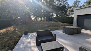 An outdoor patio area with a seating arrangement, a potted plant, and a slide in the background. - Charming country house near Saint-Valery-Sur-Somme, 6 people (Arrest)