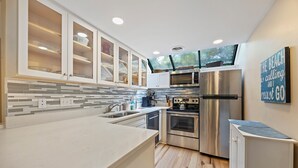 A modern kitchen with white cabinets, a stainless steel refrigerator, an oven, and a microwave.
