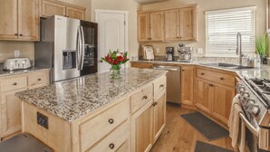 A kitchen with wooden cabinets, granite countertops, stainless steel appliances, and a window with blinds. - Sunshine Retreat-Hot Tub,Massage Chair,Espresso&EV (Bend)