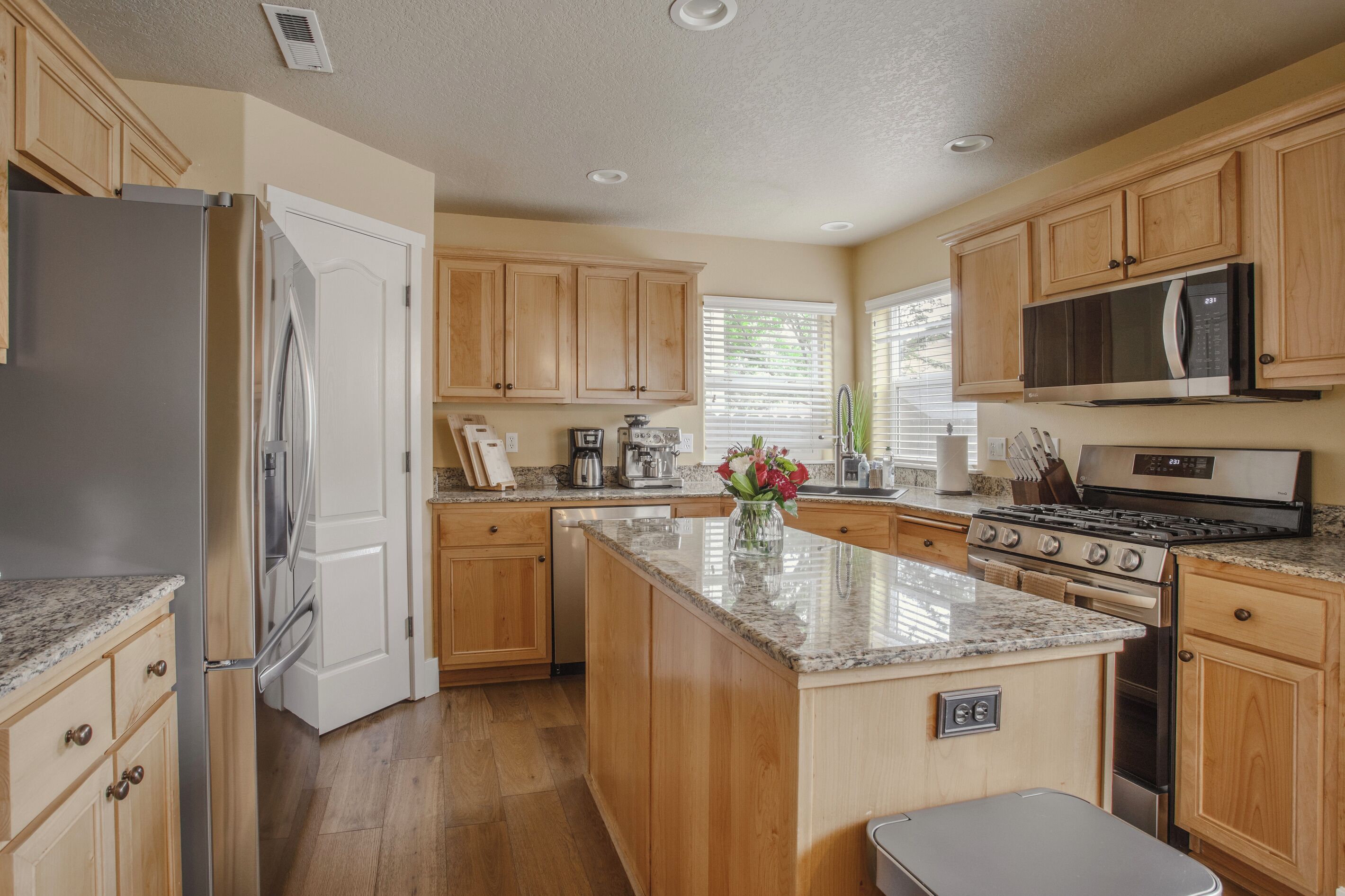 A kitchen with wooden cabinets, a stainless steel refrigerator, a microwave, and a stove.