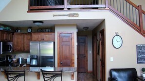 Una cocina con puerta doble, un refrigerador y un comedor con sillas.