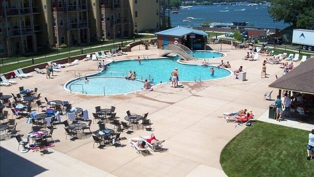 Un resort con varias piscinas, zonas de descanso y vistas a un lago.