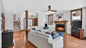 Un salón amplio con chimenea, televisión y ventilador de techo.