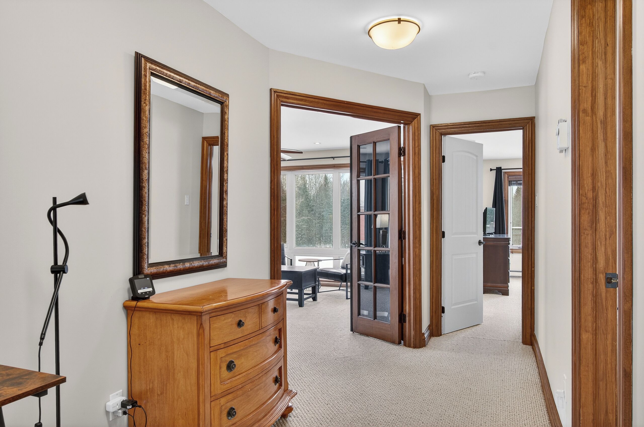 A room with a wooden dresser, a large mirror, and a door leading to another room.