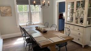 A dining room with a long wooden table, black chairs, a chandelier, and a cabinet with glass doors. - Harbor House located in the heart of Ephraim! (Ephraim)