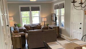 A spacious living room with a large sofa, a dining table with chairs, and a TV mounted on the wall. - Harbor House located in the heart of Ephraim! (Ephraim)
