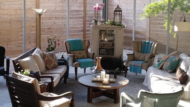 A covered patio area with wooden furniture, a central table, and a decorative cabinet. - Temporary living that feels like home where you can relax and be yourself. (Maitland)