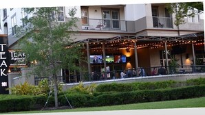 A building with a sign reading "TEAK 981" and a covered outdoor area with string lights. - Temporary living that feels like home where you can relax and be yourself. (Maitland)