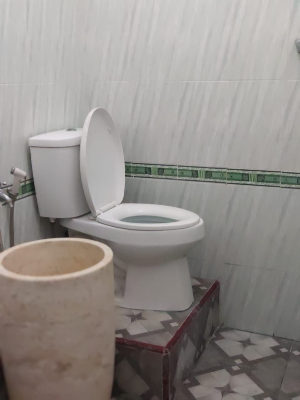 Ein Badezimmer mit Toilette, Mülleimer und Fliesenwänden.