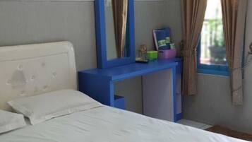 Un dormitorio con cama, un escritorio azul, un espejo y una ventana con cortinas.