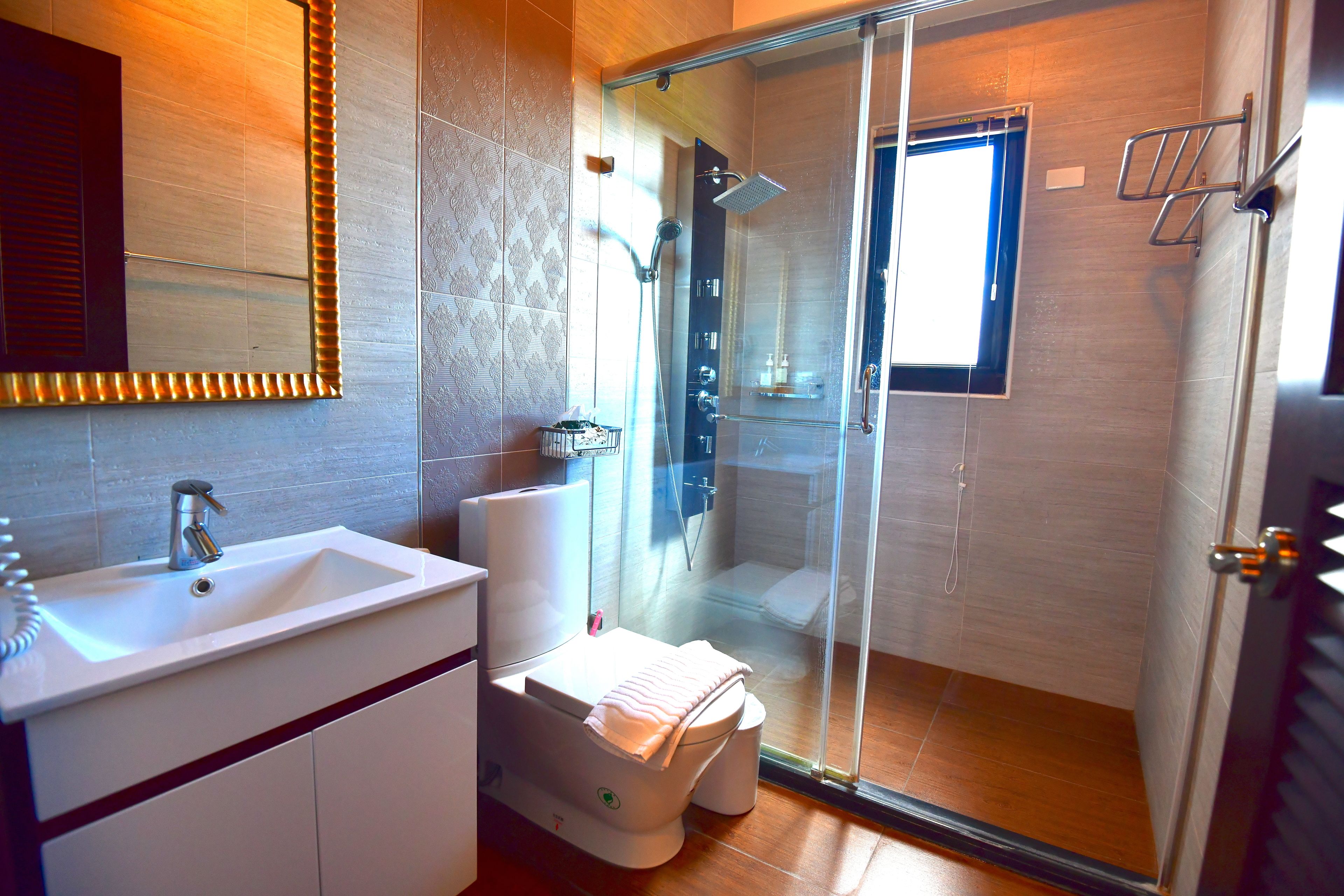 A modern bathroom with a glass-enclosed shower, a sink, and a toilet.