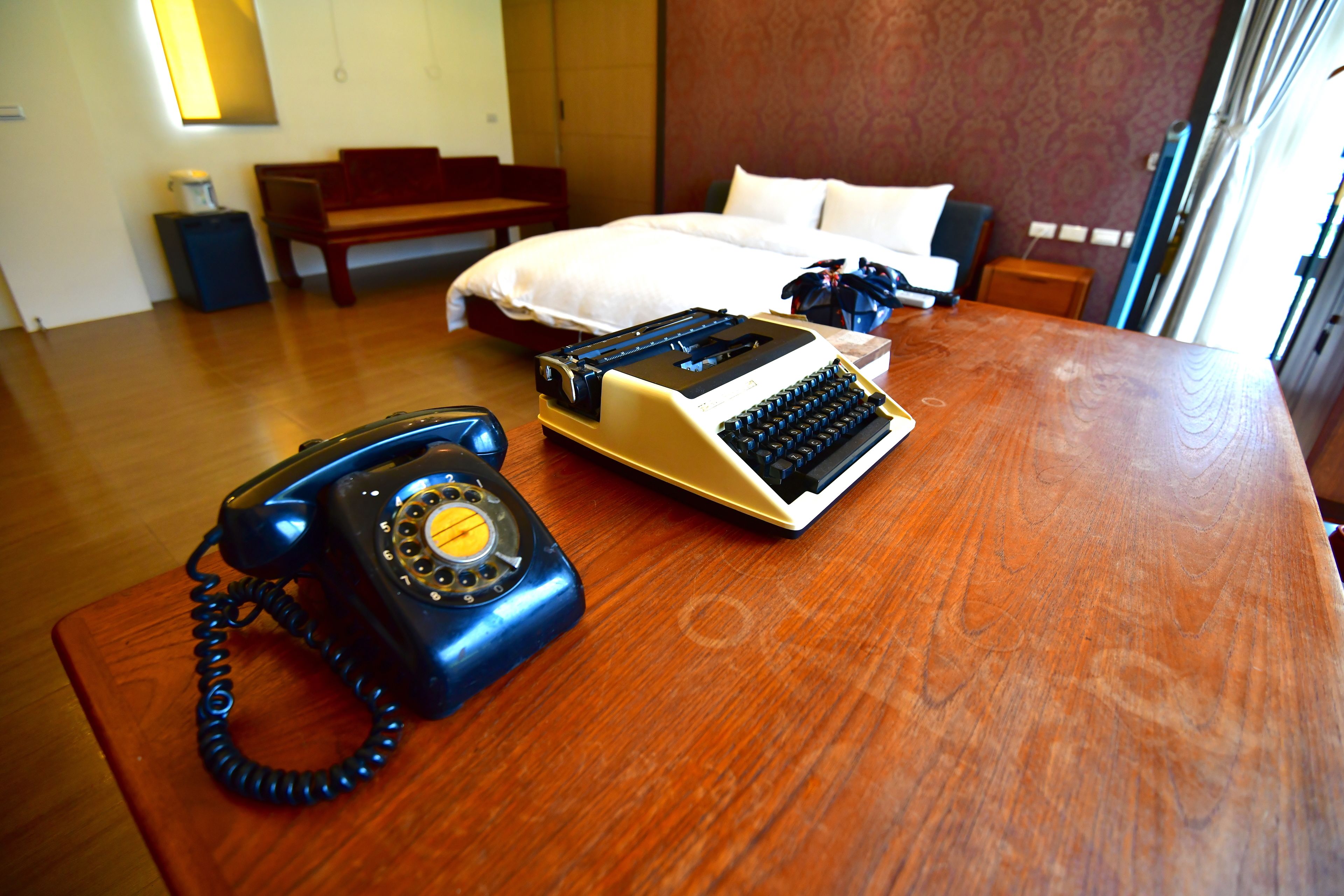 Une chambre d’hôtel avec un bureau en bois, un téléphone ancien et une machine à écrire.