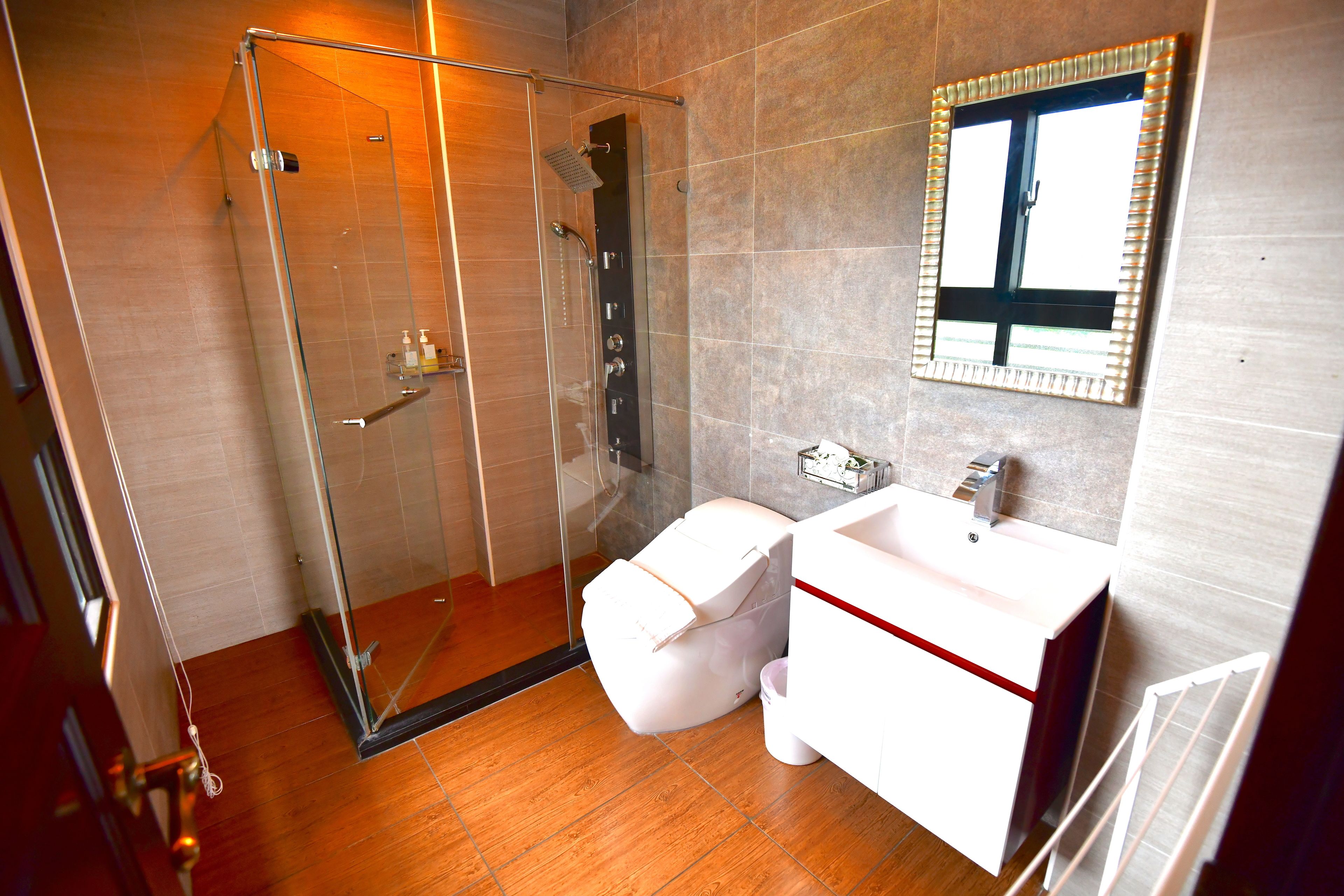 A modern bathroom with a glass-enclosed shower, a white toilet, and a sink with a mirror above it.