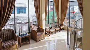Ein geräumiger Balkon mit Korbmöbeln, einem Glastisch und einem Metallgeländer.