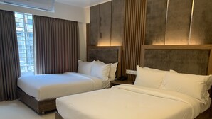 Une chambre d’hôtel avec deux lits, une grande fenêtre avec des rideaux et un design moderne agrémenté de lambris en bois.