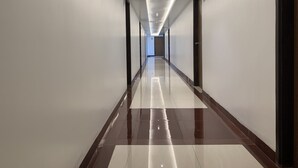 Un long couloir bien éclairé, doté d’un sol carrelé brillant et de murs sobres.