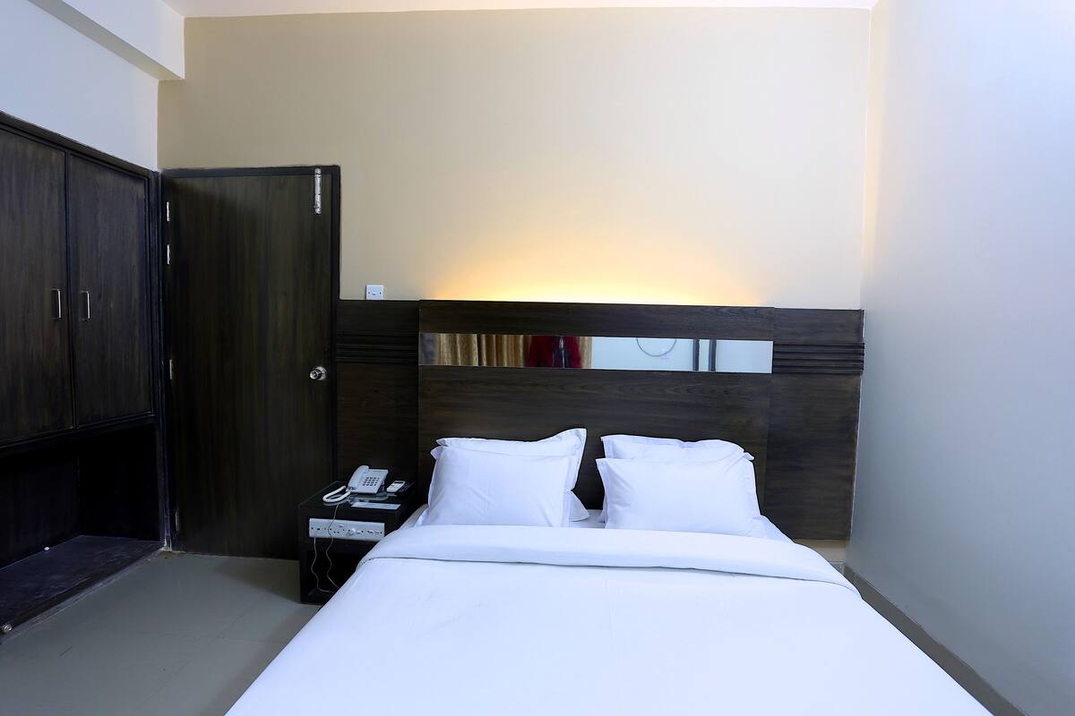 A hotel room with a bed, a nightstand, a telephone, and a wardrobe.