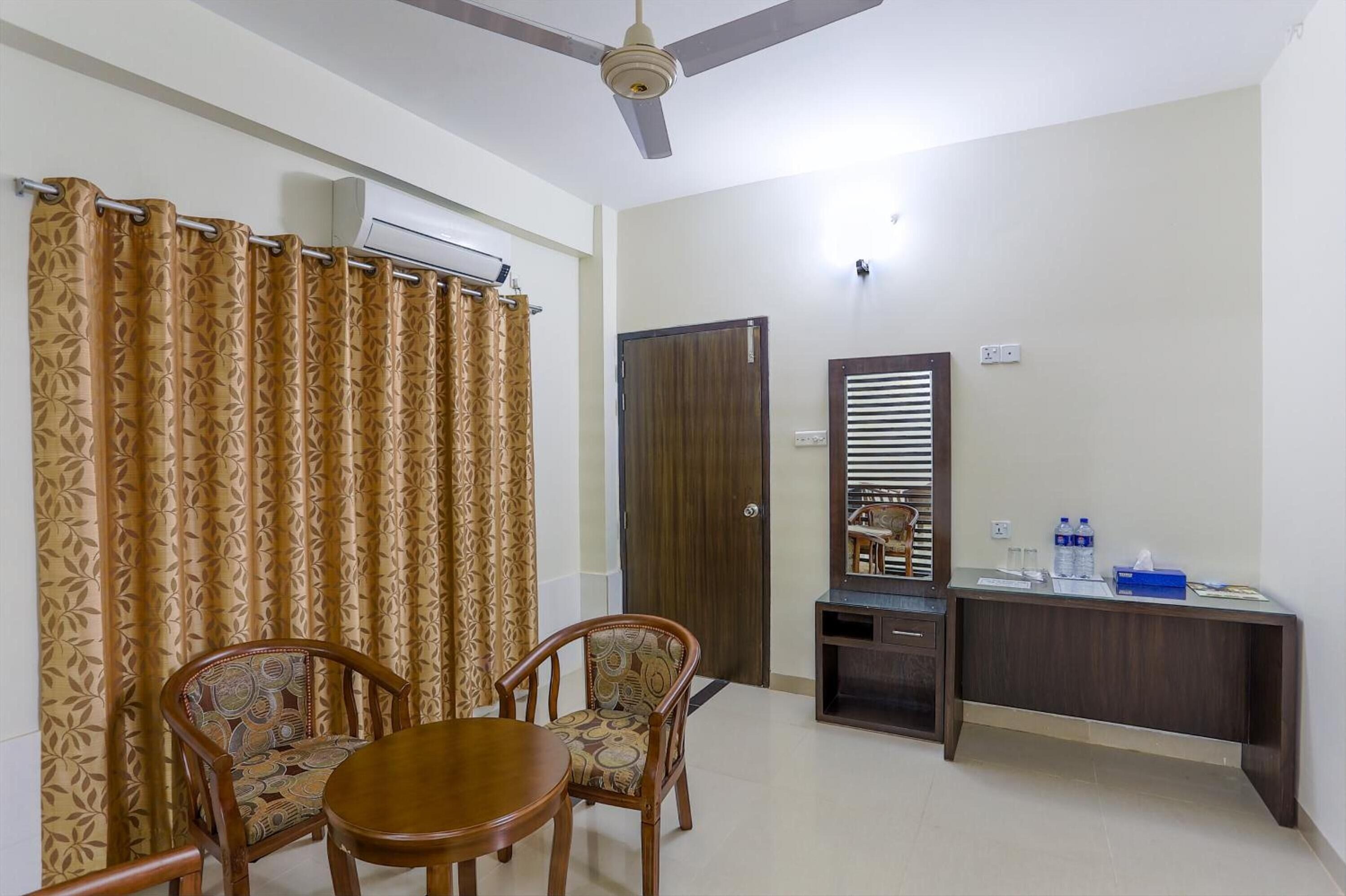 A room with a ceiling fan, a wooden desk with a mirror, a chair, and a table.