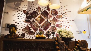 A reception desk with a Buddha statue, decorative wall art, and a potted plant. - Diamond Dorm Vietnam - Hostel (Hanoi)