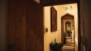 A wooden door with a geometric pattern, a potted plant, and a wall-mounted sign with a logo. - Diamond Dorm Vietnam - Hostel (Hanoi)