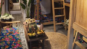 A cozy room with a bunk bed, a ladder, a small table with fruits, and a woven mat on the floor. - Diamond Dorm Vietnam - Hostel (Hanoi)