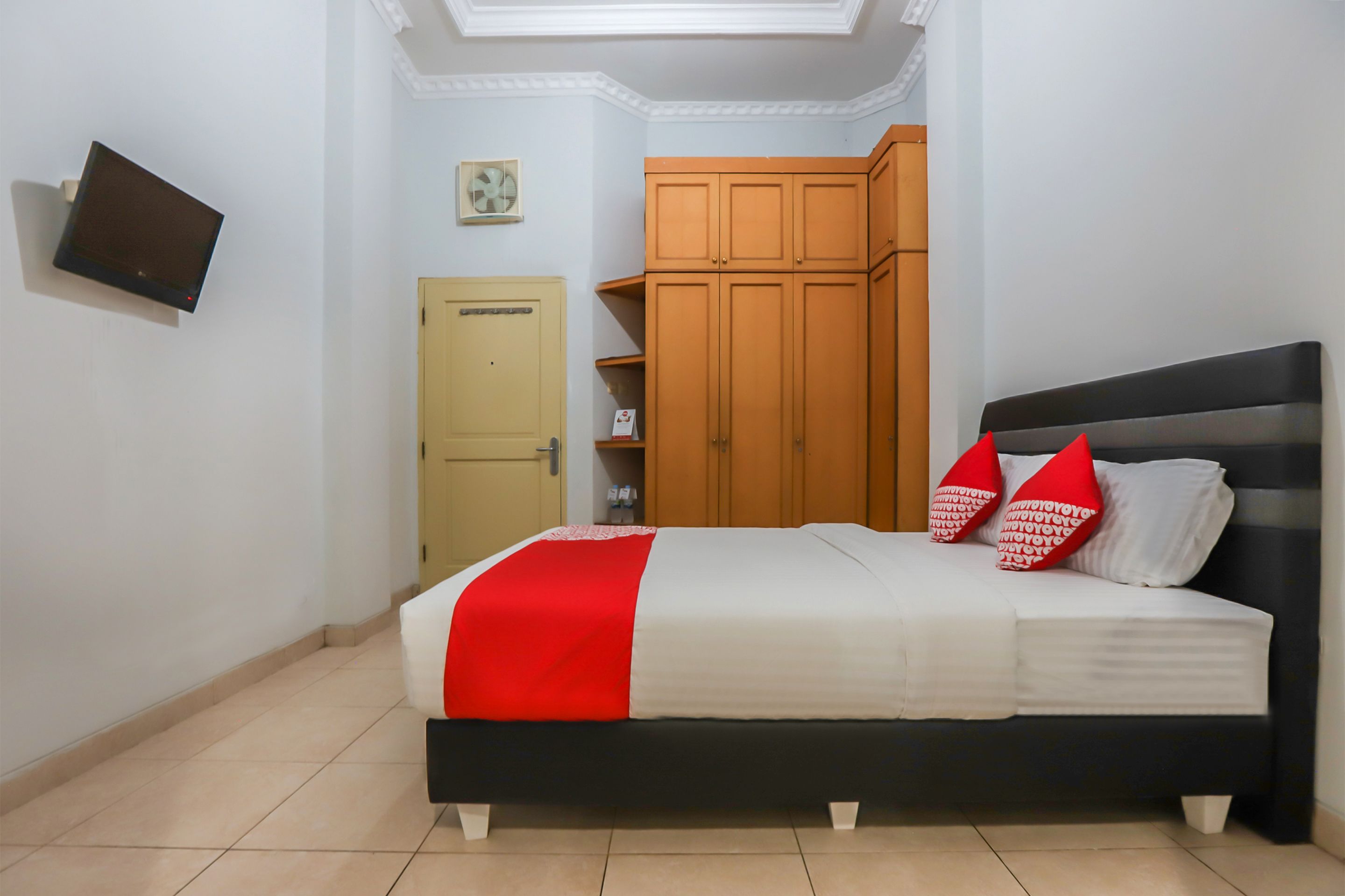Een slaapkamer met een bed, een kledingkast, een televisie en een deur.