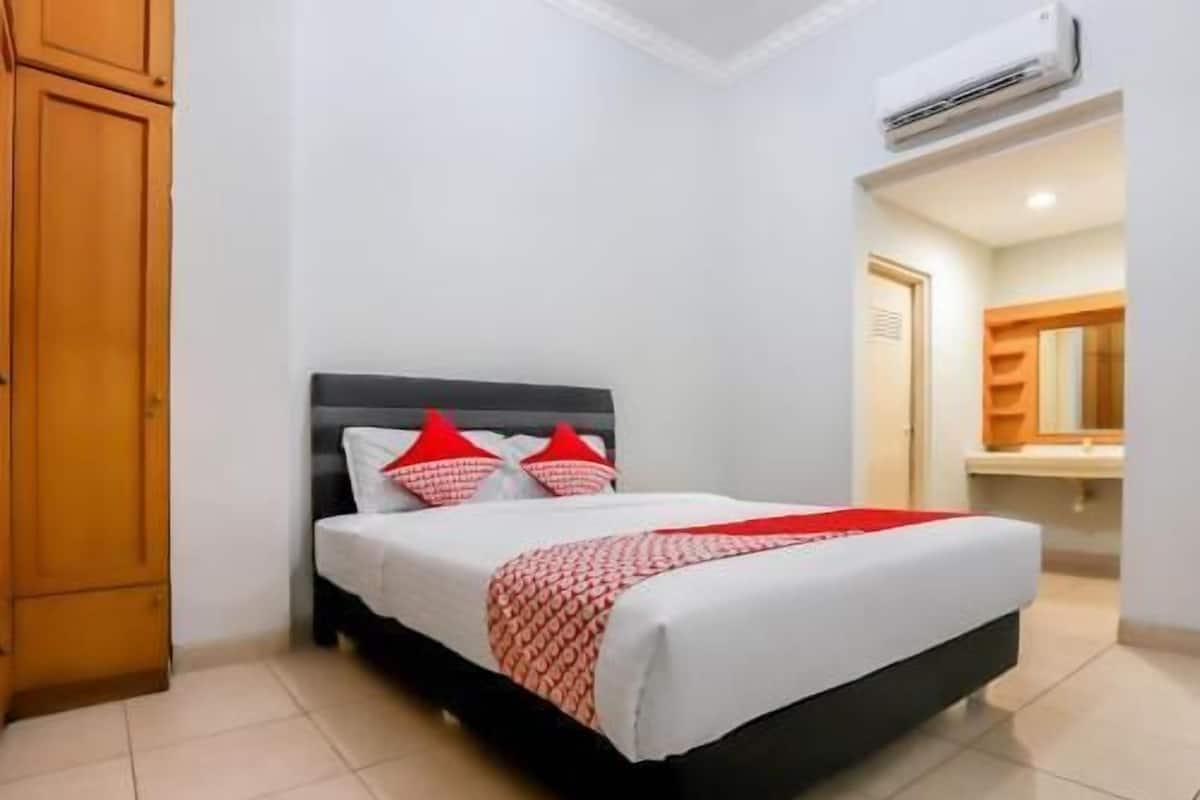 Een slaapkamer met een bed, een houten garderobe en een airconditioning.