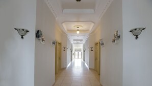 A long, narrow hallway with white walls and a tiled floor, leading to a door at the end. - Collection O Mangga Besar Near Lokasari Square Formerly 45 Residence (Jakarta)
