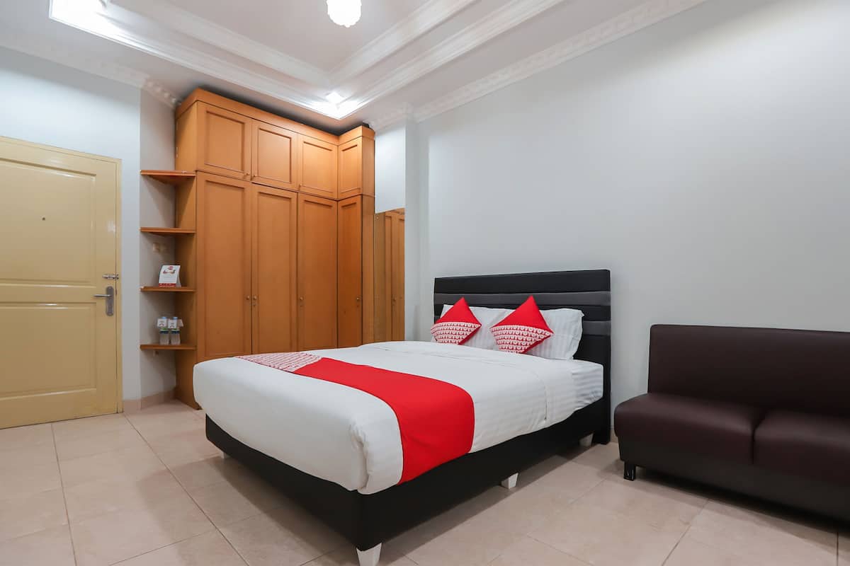 Een slaapkamer met een bed, een kledingkast, een bank en een deur.