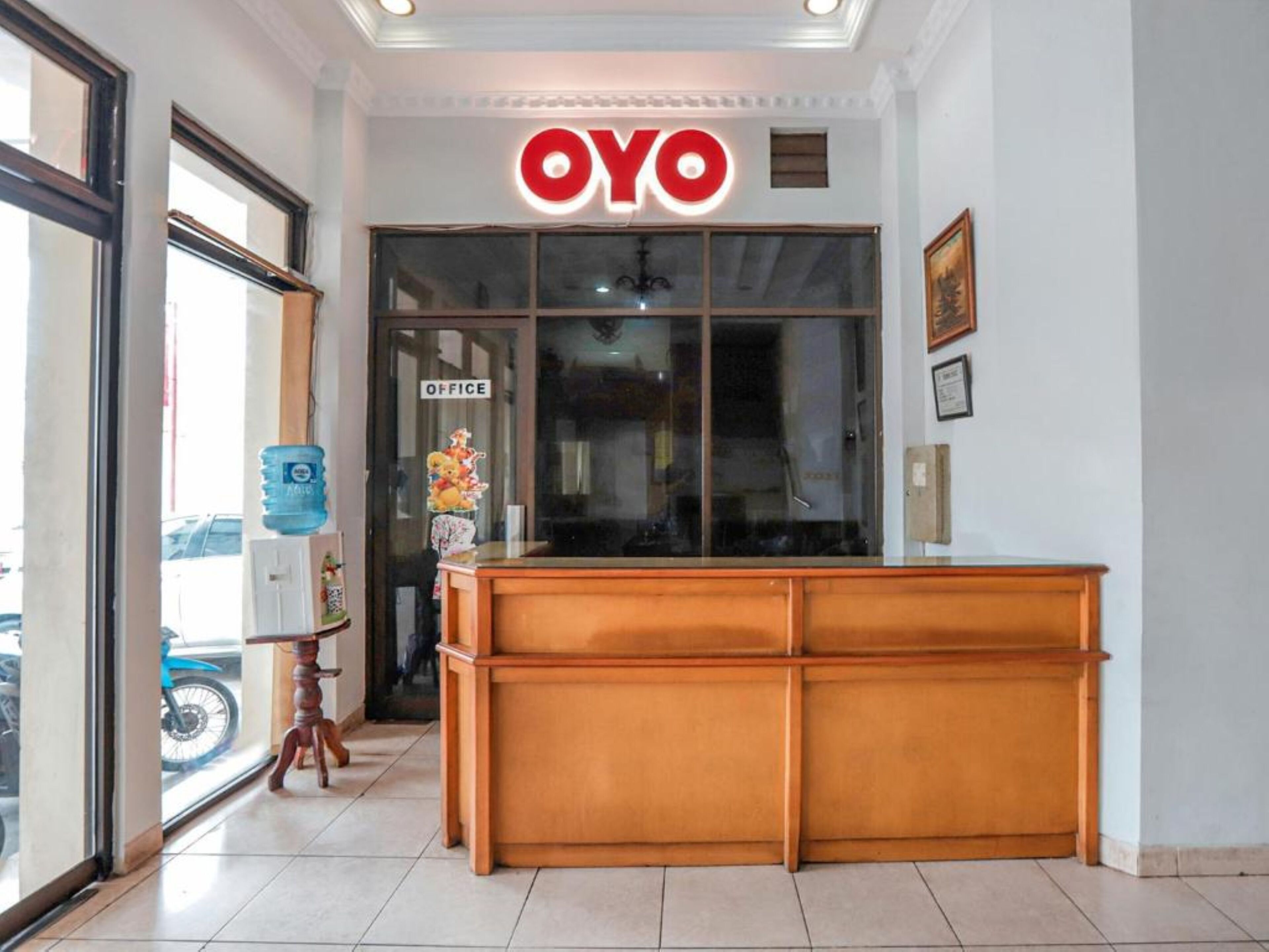 Ein Empfangsschalter mit einem Schild mit der Aufschrift 'OYO', einem Wasserspender und einem gerahmten Bild an der Wand.