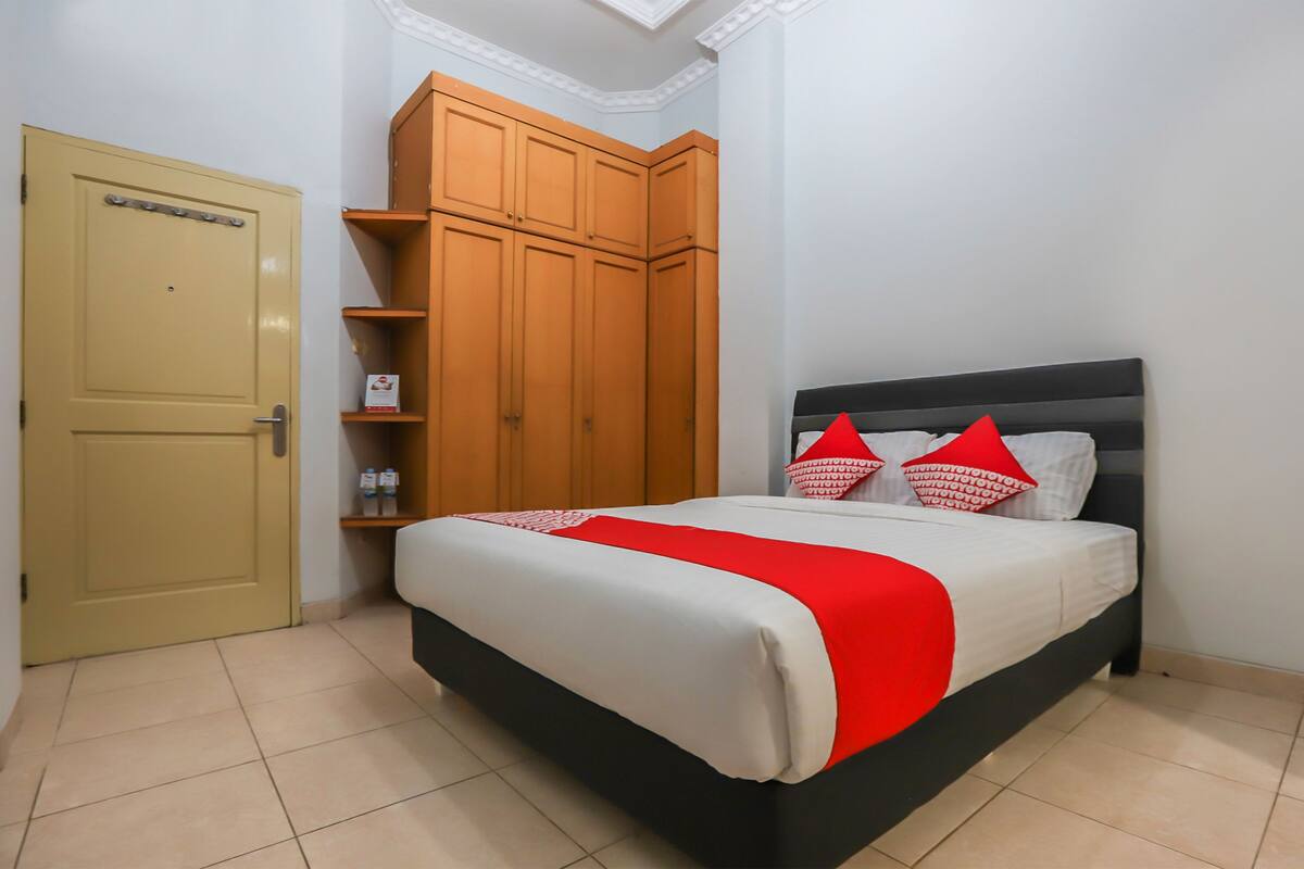 Een slaapkamer met een bed, een kledingkast en een deur.