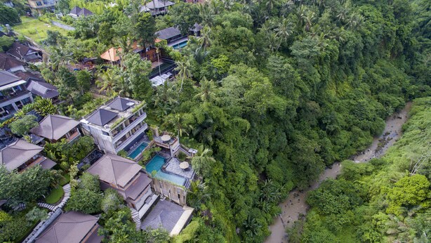 An aerial view of a resort with multiple buildings, a swimming pool, and lush greenery surrounding the area. - Ubud Paras Villa (Ubud)