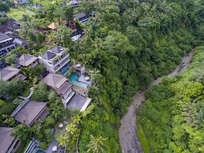 An aerial view of a resort with multiple buildings, a swimming pool, and lush greenery surrounding the area. - Ubud Paras Villa (Ubud)