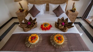 A neatly made bed with brown towels and decorative floral arrangements. - Ubud Paras Villa (Ubud)