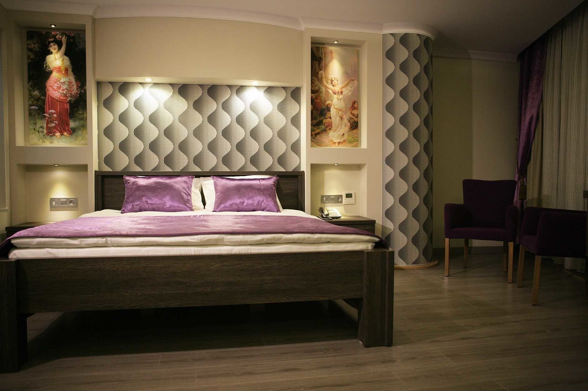 Un dormitorio moderno con una cama grande, un cabecero de diseño geométrico y obras de arte en las paredes.